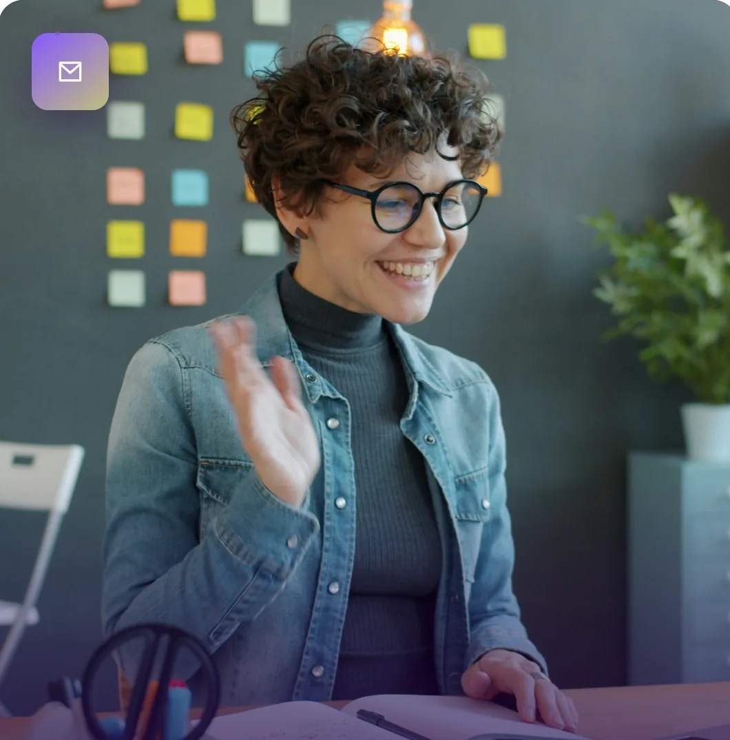 Smiling saleswoman waving during a video call at her desk